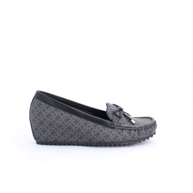 Black wedge moccasin with subtle patterns, faux leather, and rubber outsole for comfort and grip, perfect for casual and dressy occasions.